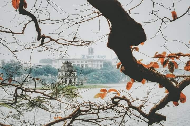 Turtle Tower standing serenely amidst morning mist on Hoan Kiem Lake. 